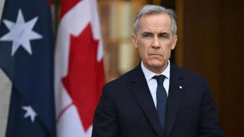 Mark Carney con traje oscuro y expresión seria ante banderas en un evento oficial